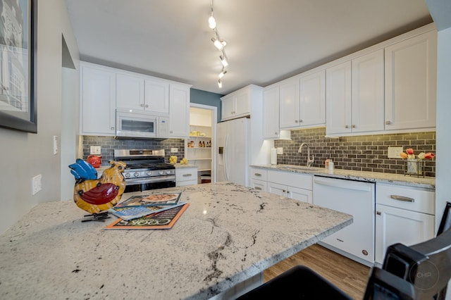 kitchen featuring light stone counters, sink, white appliances, and white cabinets