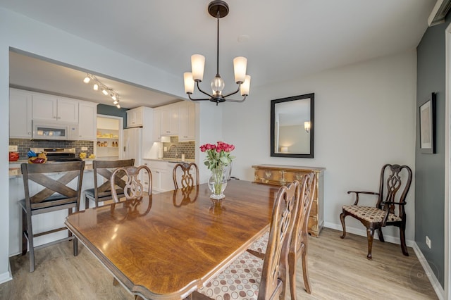 dining space with sink, light hardwood / wood-style flooring, and a notable chandelier