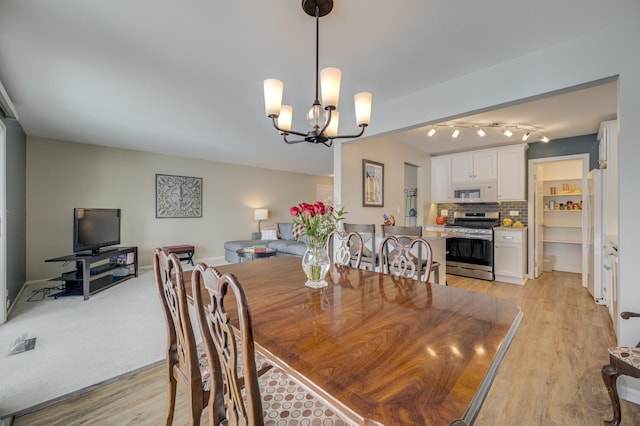 dining space with light hardwood / wood-style floors and a notable chandelier