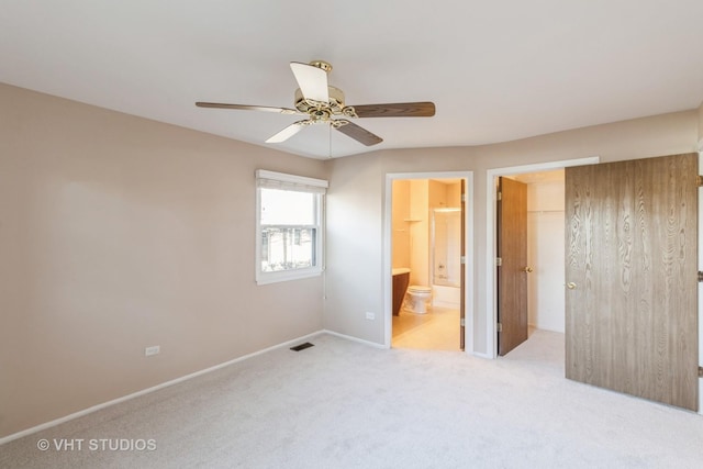 unfurnished bedroom with ceiling fan, connected bathroom, light carpet, a spacious closet, and a closet