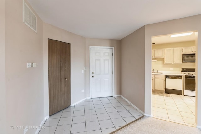 interior space featuring light tile patterned flooring, white appliances, and sink