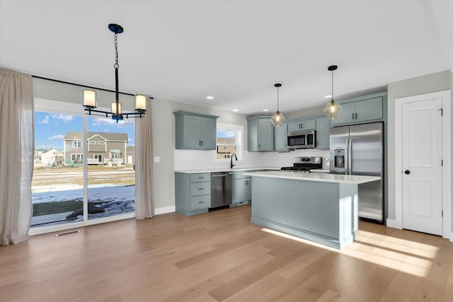 kitchen featuring pendant lighting, stainless steel appliances, a center island, and decorative backsplash