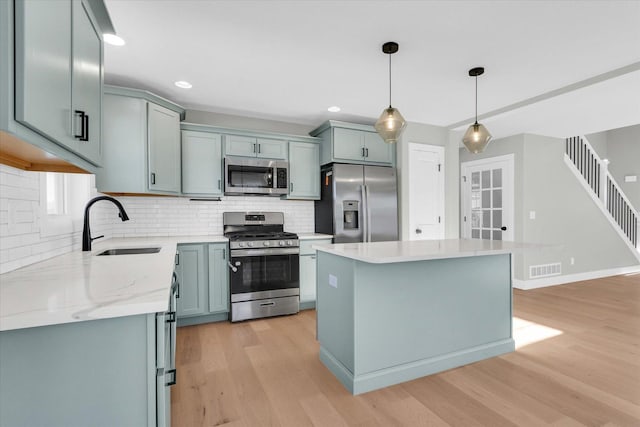 kitchen featuring sink, decorative light fixtures, a center island, light hardwood / wood-style flooring, and appliances with stainless steel finishes