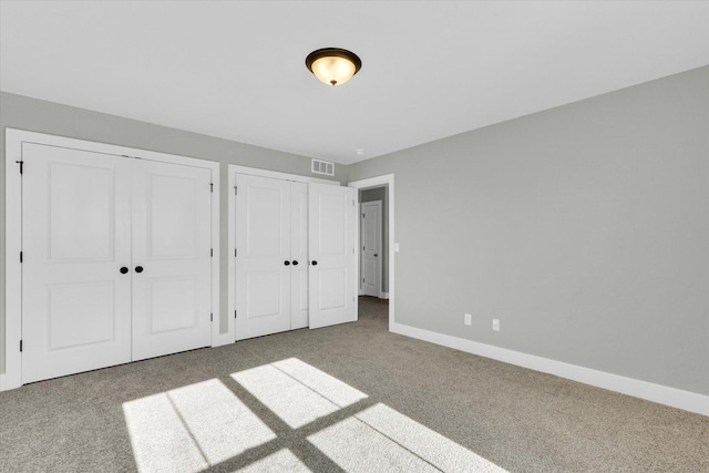 unfurnished bedroom featuring carpet floors and two closets