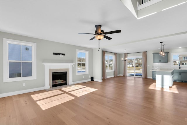 unfurnished living room with a healthy amount of sunlight, a high end fireplace, and light hardwood / wood-style flooring