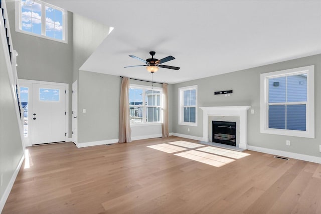 unfurnished living room featuring ceiling fan, a premium fireplace, and light hardwood / wood-style flooring