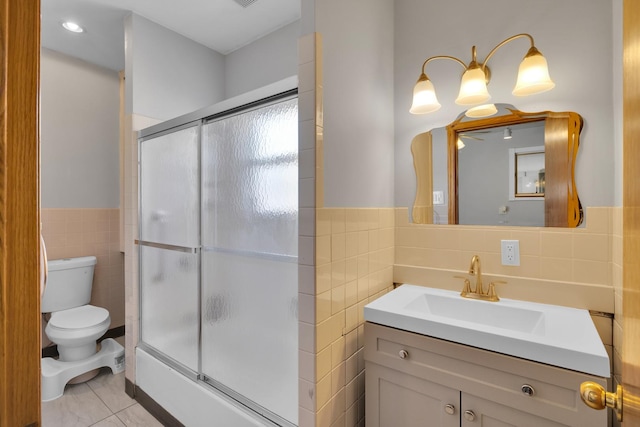 bathroom featuring tile patterned floors, toilet, a shower with shower door, tile walls, and vanity