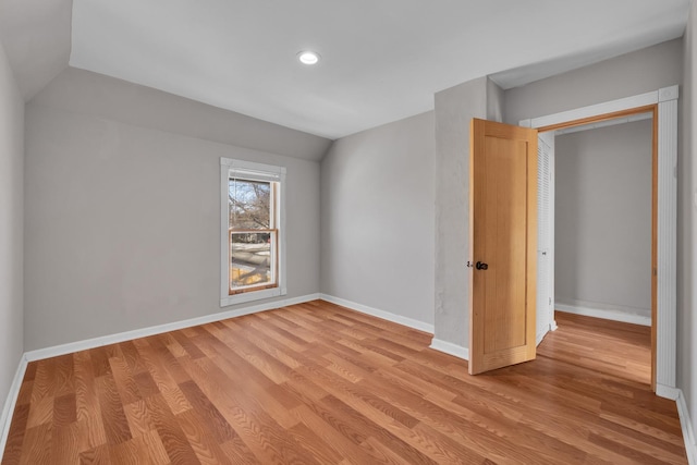 unfurnished bedroom with vaulted ceiling, light hardwood / wood-style floors, and a closet