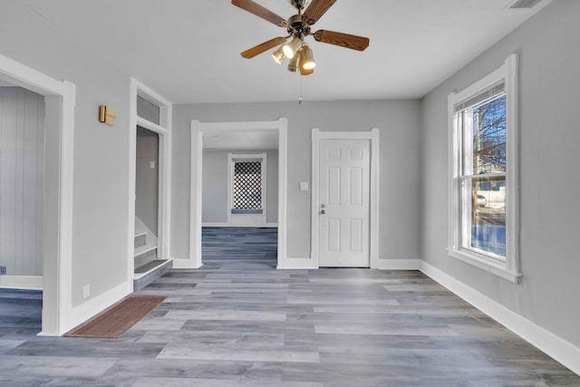 empty room featuring ceiling fan, plenty of natural light, and light wood-type flooring