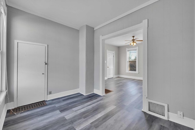 interior space with dark wood-type flooring, wooden walls, and ceiling fan