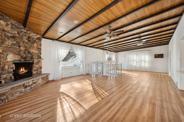 unfurnished living room featuring plenty of natural light, a fireplace, light hardwood / wood-style floors, and beam ceiling