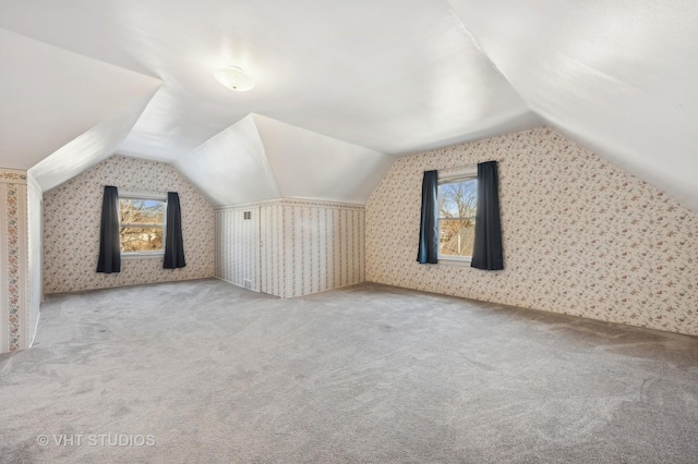 additional living space featuring lofted ceiling and light carpet