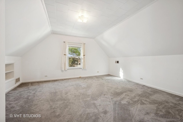 additional living space with vaulted ceiling, carpet flooring, and built in features