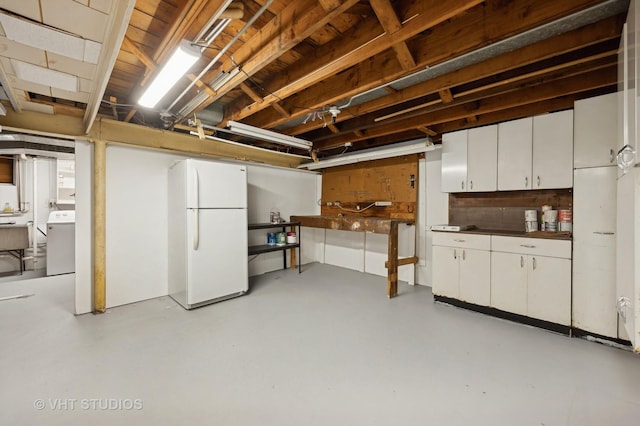 basement with washer / clothes dryer and white fridge