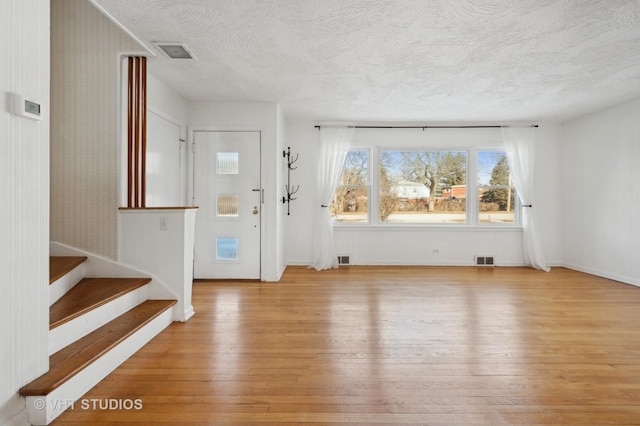 foyer entrance featuring a textured ceiling and light wood-type flooring