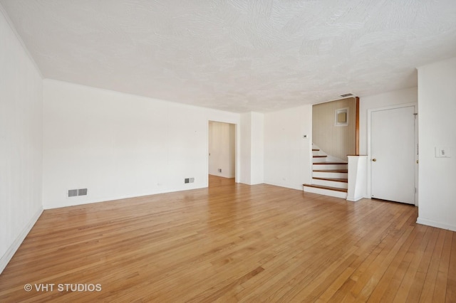 spare room featuring a textured ceiling and light wood-type flooring