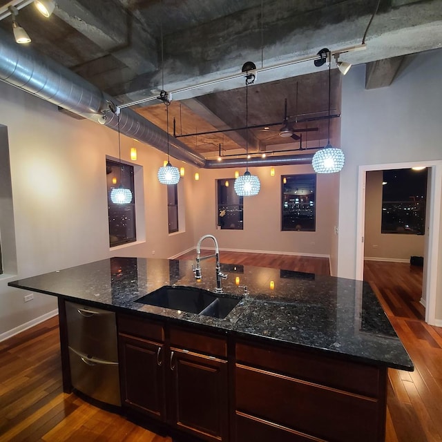 kitchen with sink, decorative light fixtures, dark wood-type flooring, and dark stone counters