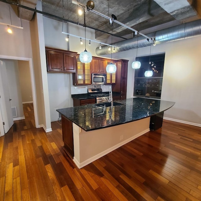 kitchen with appliances with stainless steel finishes, decorative light fixtures, sink, and dark stone counters