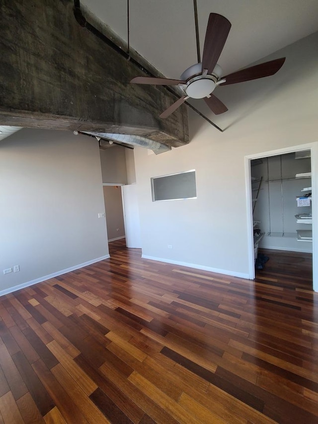 interior space with a towering ceiling, dark wood-type flooring, and ceiling fan