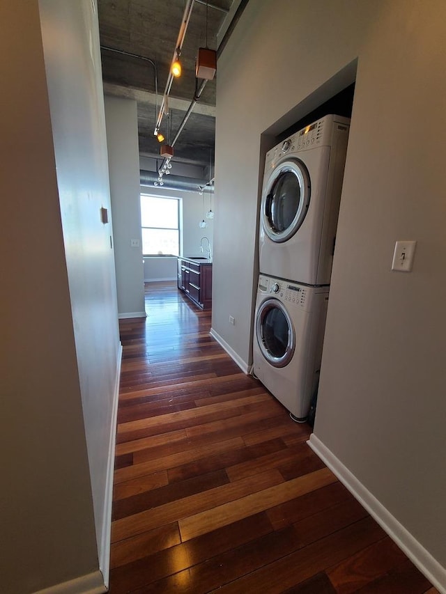 laundry room with stacked washer / drying machine, dark hardwood / wood-style flooring, and sink