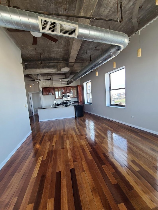 unfurnished living room featuring sink, dark wood-type flooring, and ceiling fan