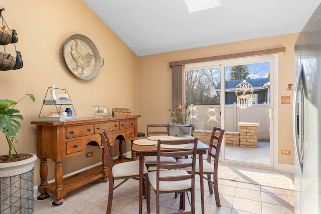 dining area with lofted ceiling with skylight and light tile patterned flooring