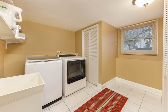 clothes washing area with light tile patterned floors and washer and clothes dryer