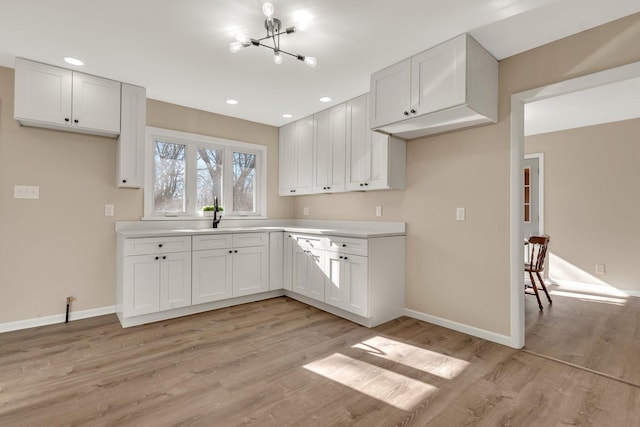 kitchen with sink, white cabinets, and light hardwood / wood-style flooring