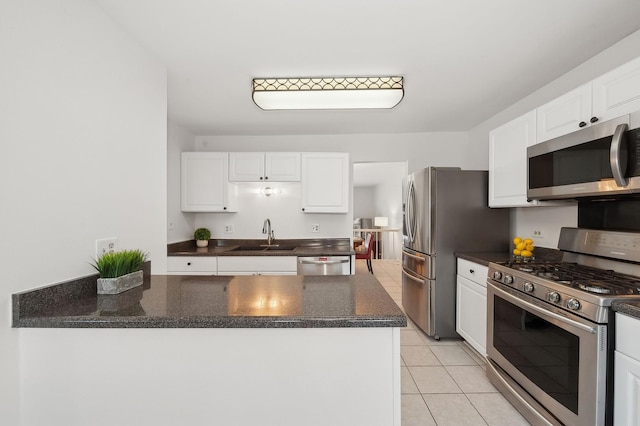 kitchen with appliances with stainless steel finishes, white cabinets, a sink, and light tile patterned flooring