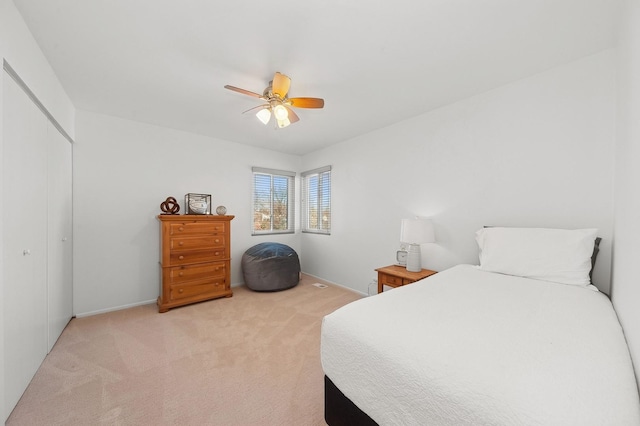 bedroom with a ceiling fan, a closet, and light colored carpet