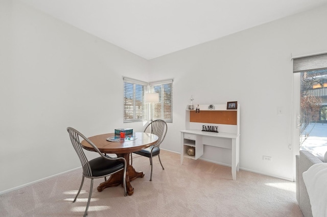 dining room featuring light carpet, a healthy amount of sunlight, and baseboards