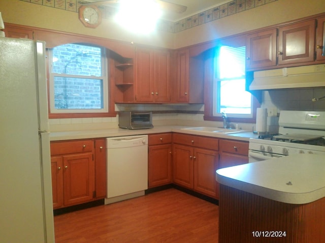 kitchen featuring white appliances, wood-type flooring, sink, and backsplash