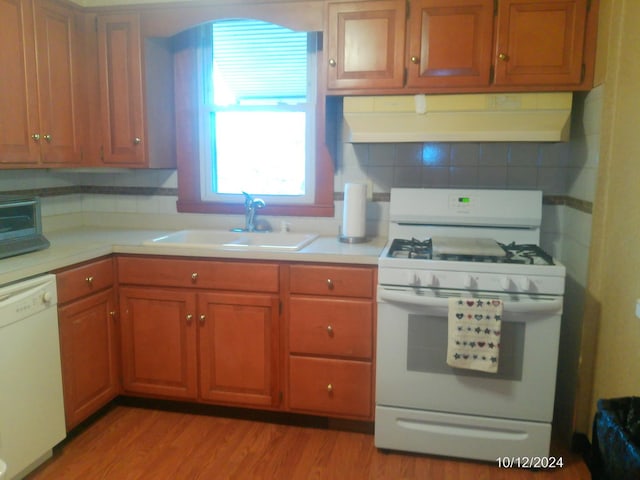 kitchen with tasteful backsplash, white appliances, light hardwood / wood-style floors, and sink