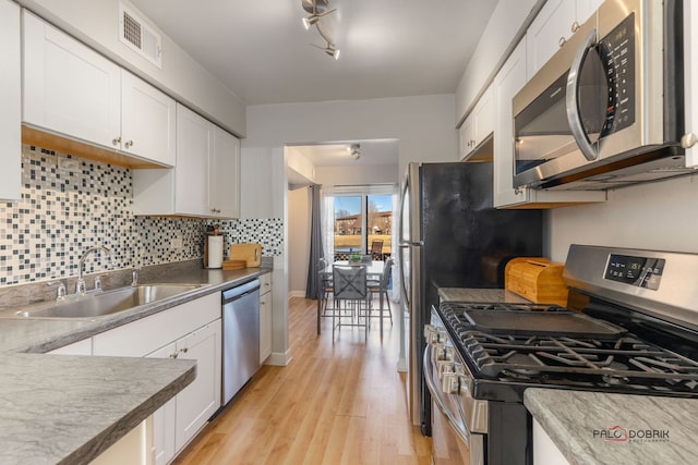 kitchen featuring appliances with stainless steel finishes, light hardwood / wood-style floors, sink, and white cabinets