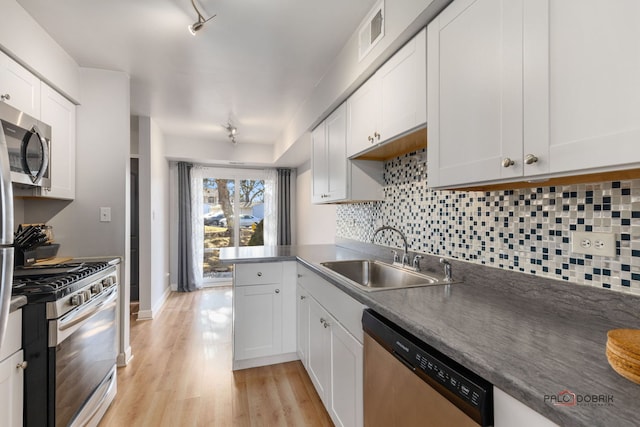 kitchen featuring sink, stainless steel appliances, kitchen peninsula, and white cabinets