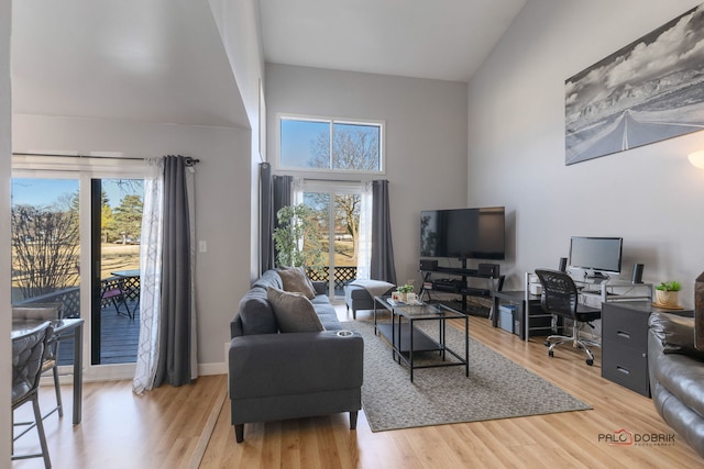 living room featuring light hardwood / wood-style flooring, a healthy amount of sunlight, and a high ceiling