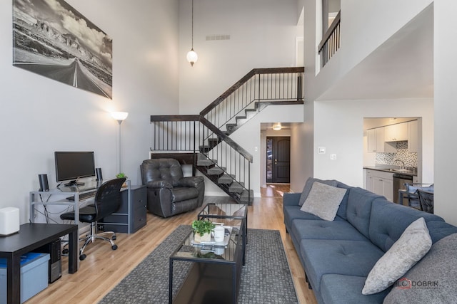 living room featuring a high ceiling and light hardwood / wood-style flooring