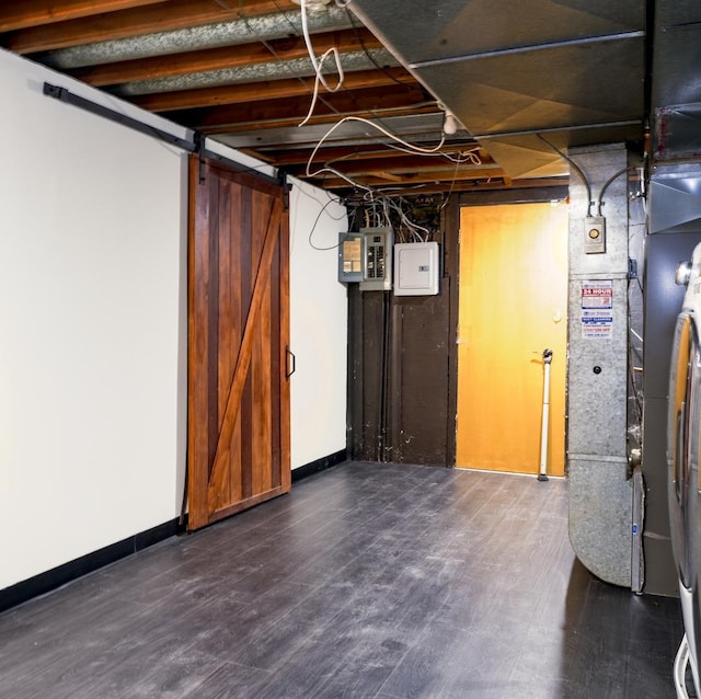 basement featuring a barn door, dark hardwood / wood-style flooring, and electric panel