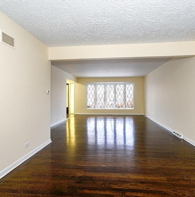 unfurnished room with dark hardwood / wood-style flooring and a textured ceiling