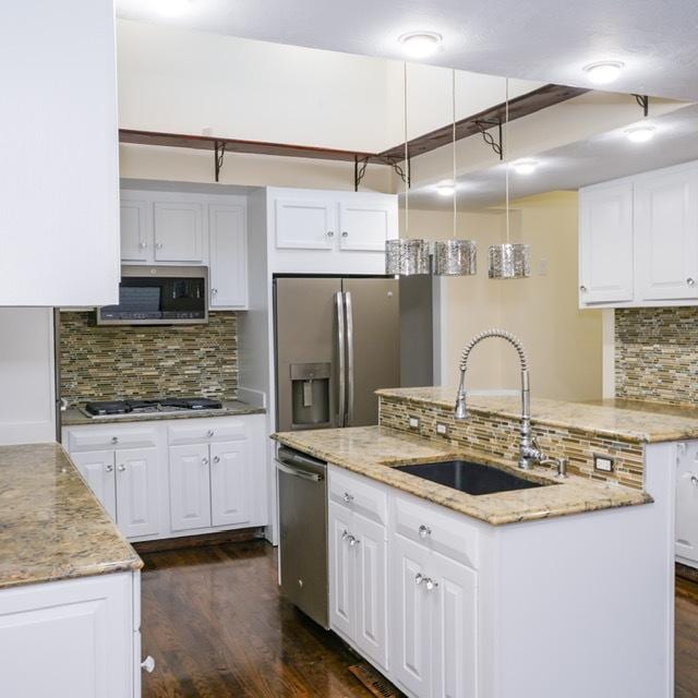 kitchen featuring backsplash, stainless steel appliances, an island with sink, and white cabinets