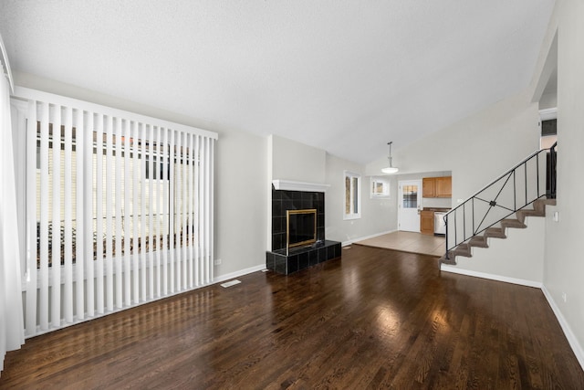 unfurnished living room with vaulted ceiling, plenty of natural light, hardwood / wood-style floors, and a tile fireplace