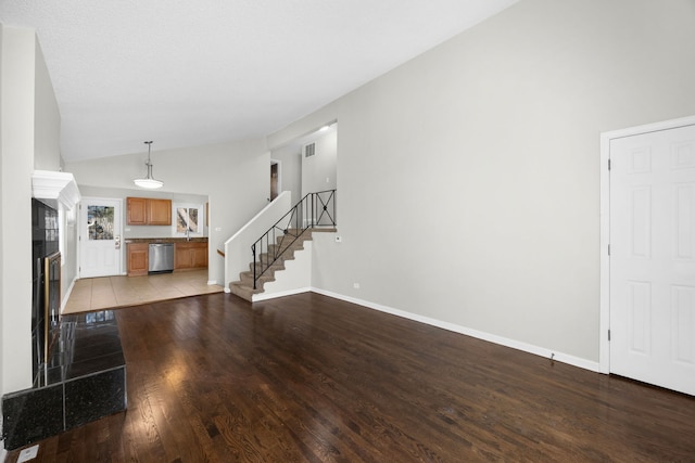 unfurnished living room with vaulted ceiling, sink, and light hardwood / wood-style floors