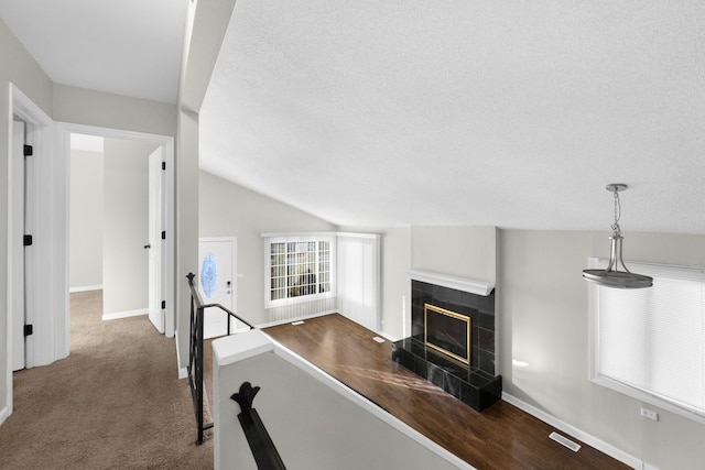 hall featuring lofted ceiling, a textured ceiling, and dark colored carpet