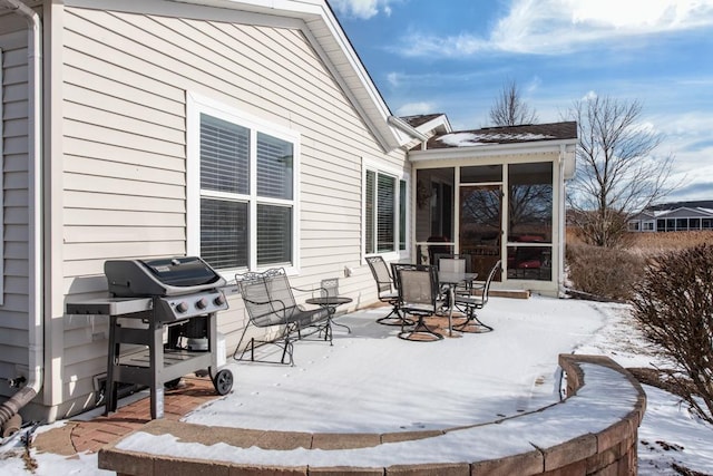 snow covered patio featuring a grill and a sunroom