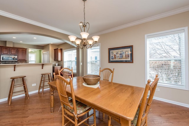 dining space with ornamental molding, light hardwood / wood-style flooring, and a notable chandelier