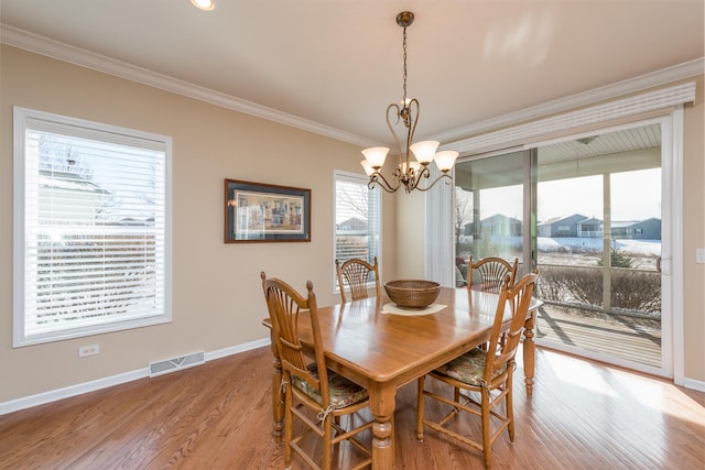 dining area with crown molding, a chandelier, and light wood-type flooring