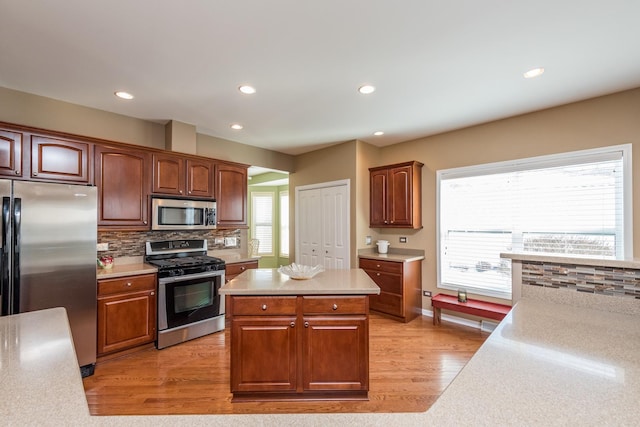 kitchen with tasteful backsplash, light hardwood / wood-style floors, stainless steel appliances, and a center island