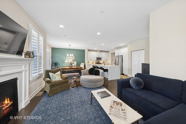 living area featuring an inviting chandelier, a fireplace, wood finished floors, and recessed lighting