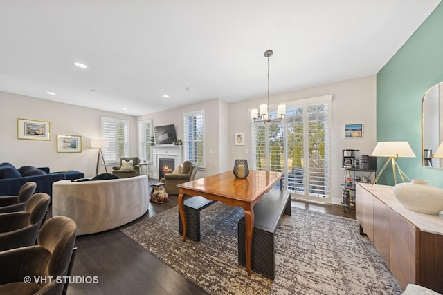 dining room featuring a lit fireplace, a chandelier, dark wood finished floors, and recessed lighting