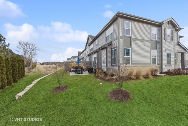 view of side of property featuring a patio area, fence, and a lawn